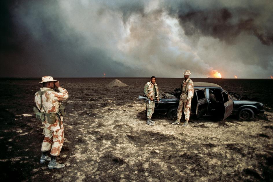 KUWAIT_-Gulf-war_-Burgan-oil-fields_-U_S_-Marines-pose-for-a-photo-in-front-of-a-burned-vehicle-containing-a-charred-corpse_-1991-Bruno-Barbey